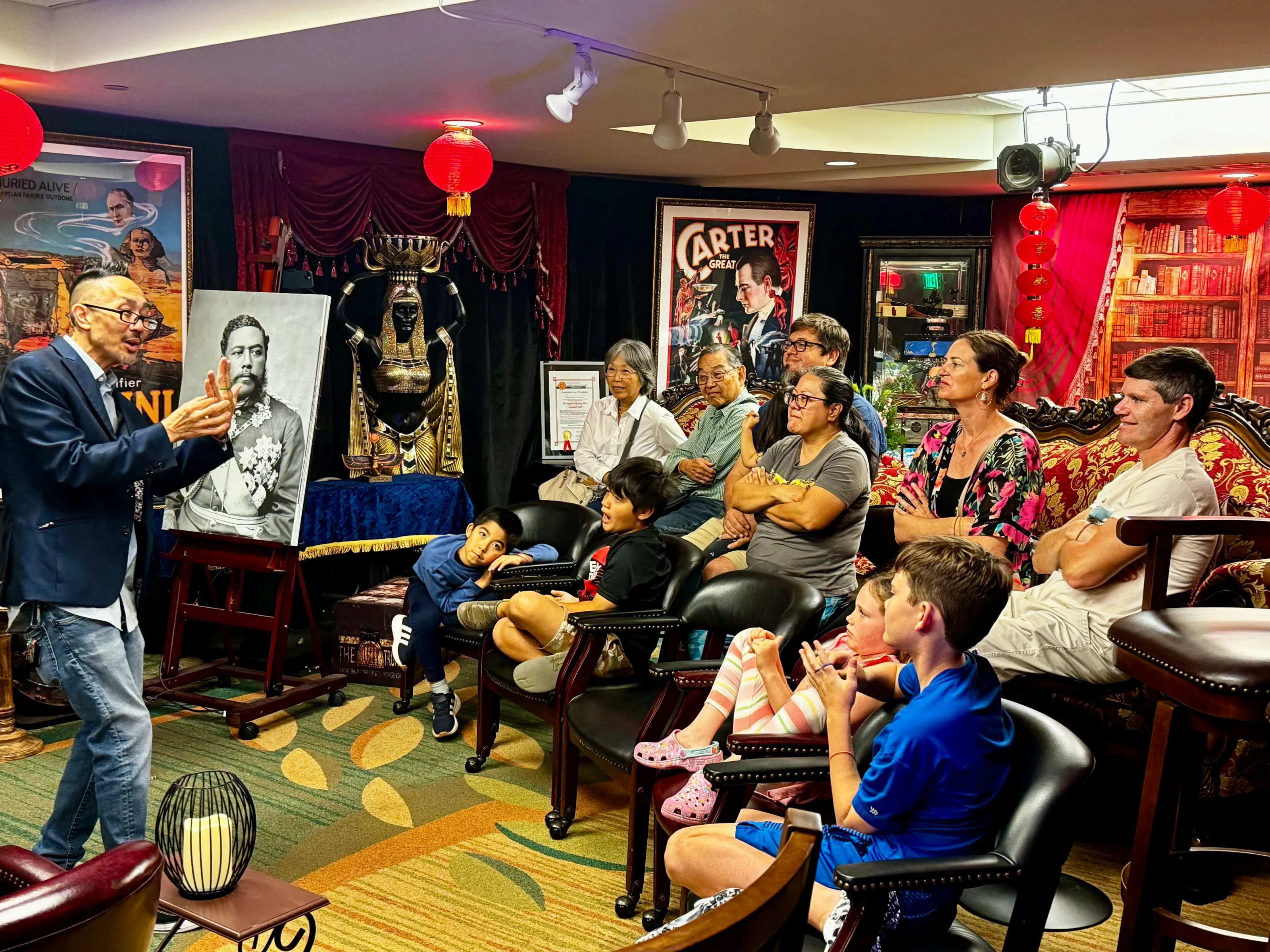 Magician performing for a captivated audience, including children, in a vintage-themed performance space.