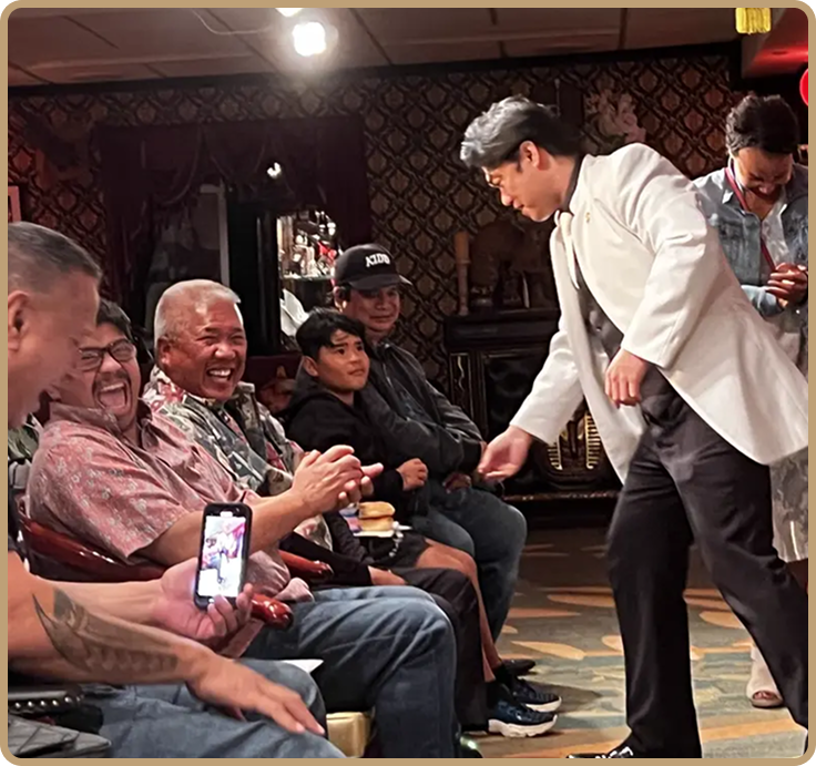 A magician performs a trick on the audience, who are laughing and enjoying the show.