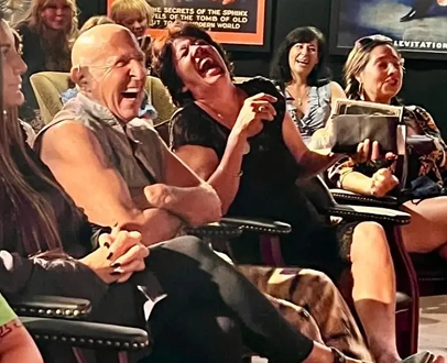 Audience laughing and enjoying a magic show, fully engaged in the performance with expressions of joy and amusement.