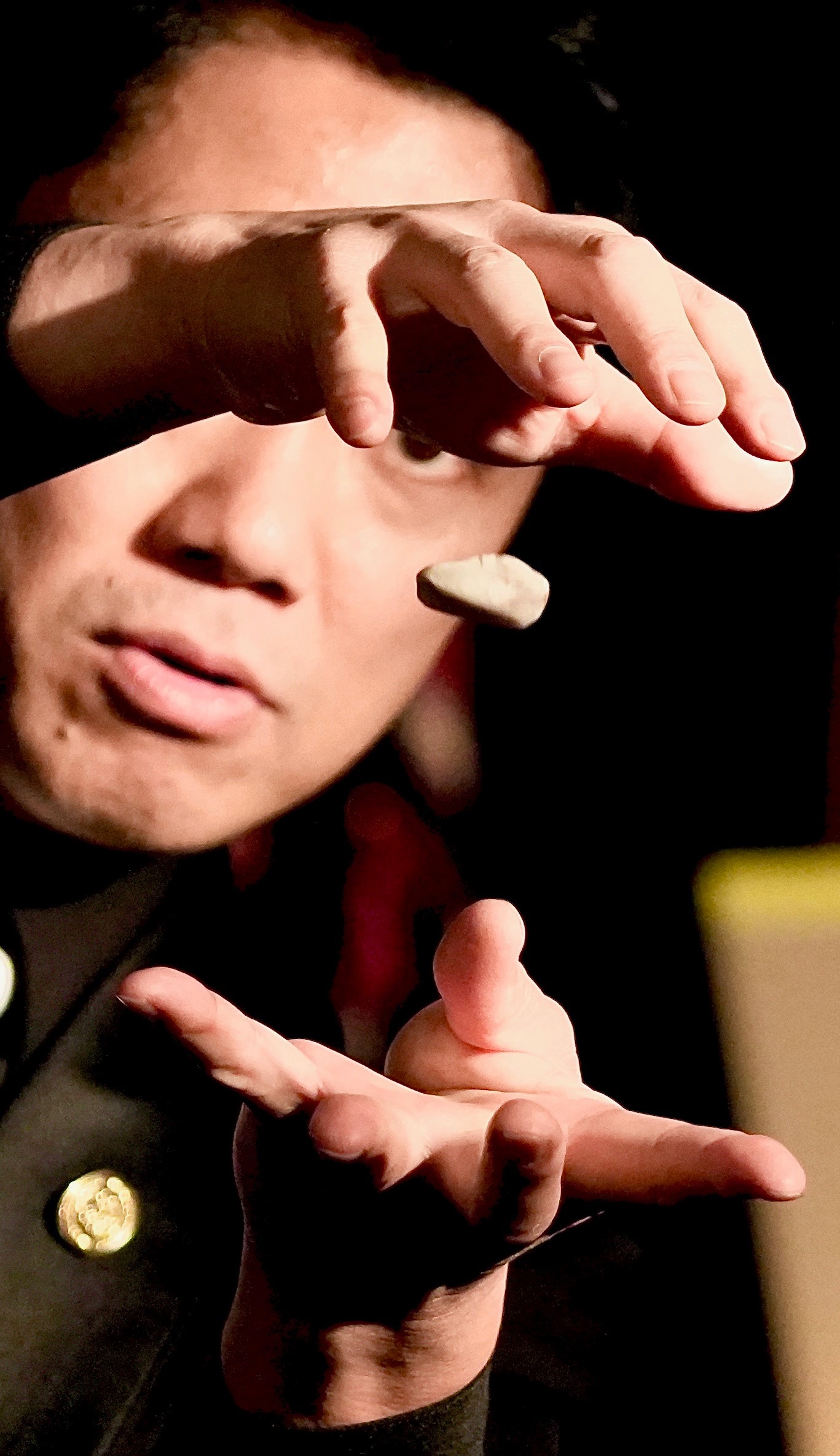 Magician performing an illusion with a levitating object, showcasing sleight of hand during a close-up magic show.