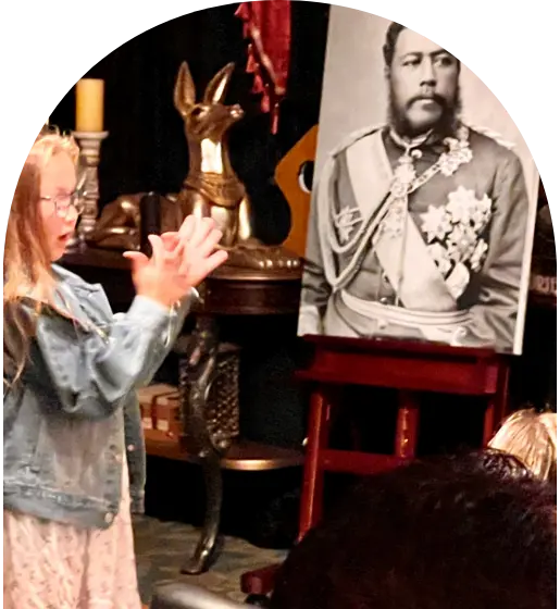 Child clapping near a portrait of a bearded man in uniform on an easel indoors.