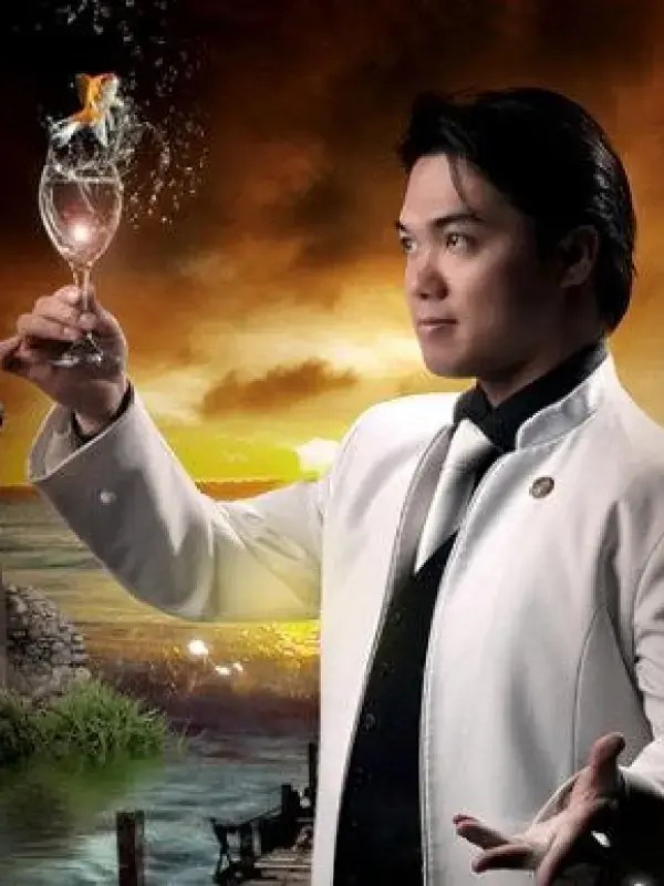 Person in white suit holding a flaming glass with a sunset backdrop.